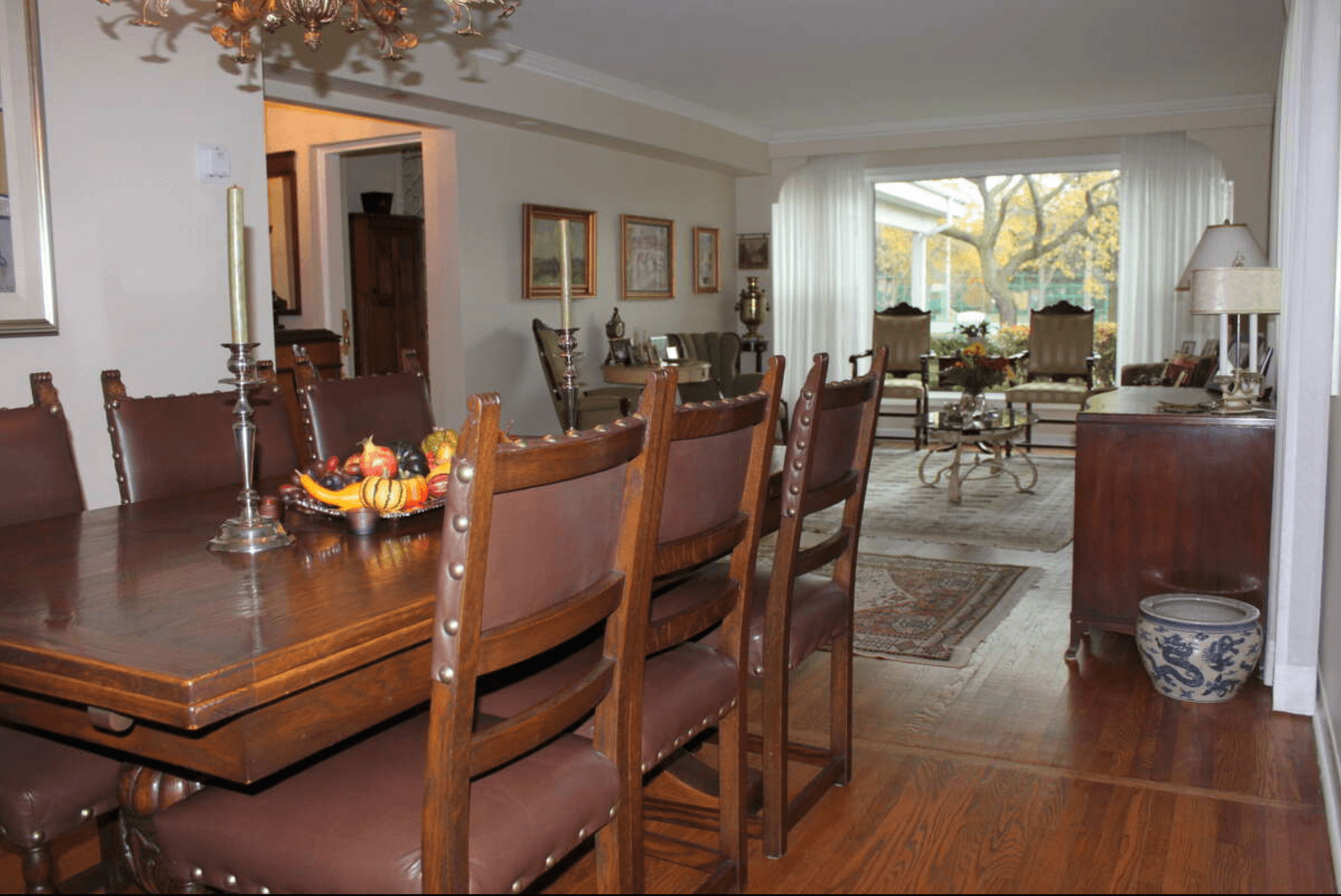 Traditional dining room with leather chairs and wooden table opening into a sunlit living area.