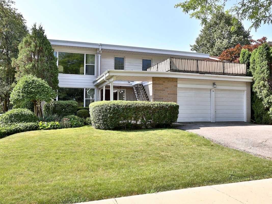 Modern two-story white house with a two-car garage, balcony, and a manicured green lawn.